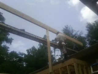 Carpenter setting a ridge beam over a new addition frame — Ice Dam Removal by Roofing Brothers in Grimesland