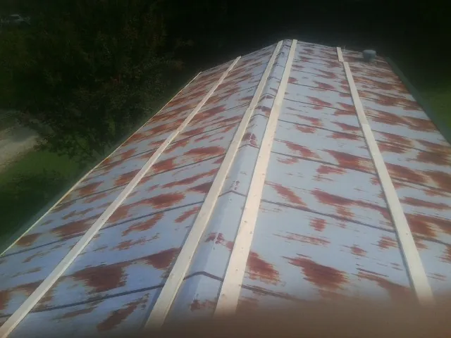 Rusted metal roof panels with new wood purlins before replacement — Storm Damage Roof Repair in Grimesland by Roofing Brothers