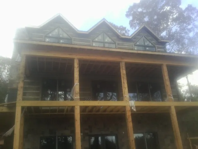 Dormers and porch framing on a large log home under construction — Roof Coating work by our crew in Grimesland