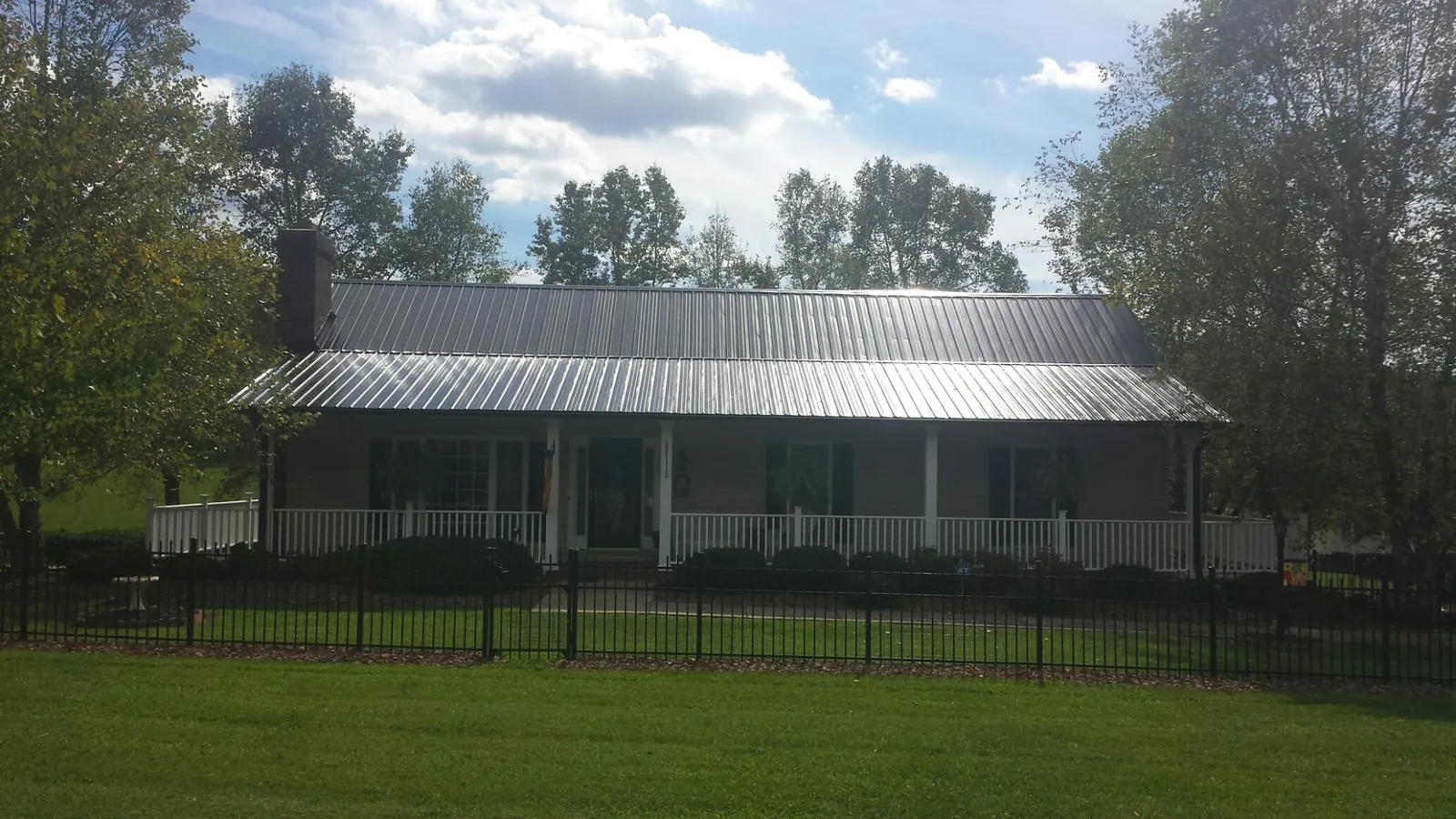 Gray metal roof on a brick ranch with a full width front porch — Gutter Guard Installation work by our crew in Grimesland
