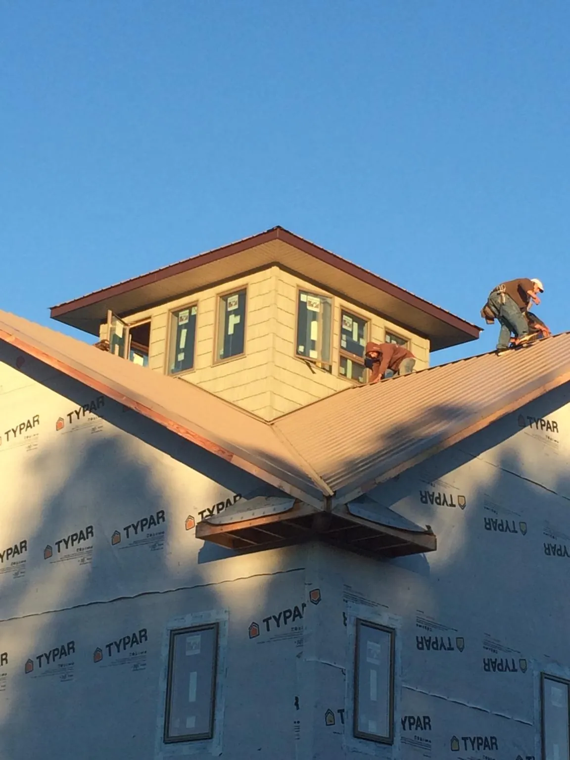 Roofers working around a rooftop cupola on a new metal roof at sunset — Roof Waterproofing in Grimesland by Roofing Brothers